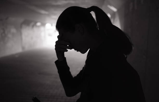 Sad lonely crying female standing in a dark tunnel.
